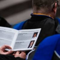 A faculty member reading the program in the audience